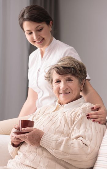 Young female caregiver taking care of older woman